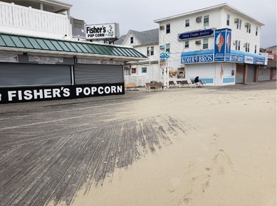 shutters closed on Fisher's Popcorn location on empty and partially sand covered OC boardwalk